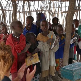 Klaslokaal van houten stokken en Tanzaniaanse kinderen die zingen. Heel indrukwekkend