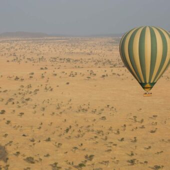 gote luchtballon met geel en groen boven de serengeti genomen vanuit een andere luchtballon