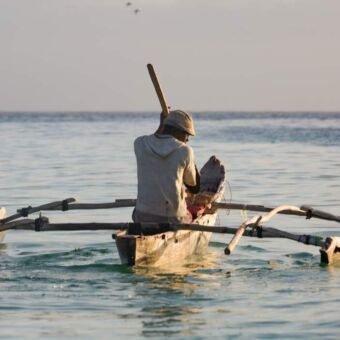 visser met een petje op in een traditioneel vissersbootje midden op het meer