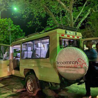 bij kunstlicht een safari auto van droomreis tanzania met een gids die de auto aan het inpakken is