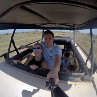 twee gasten van droomreis tanzania die staan in een safari auto met het dak open tijdens een gamedrive op de serengeti