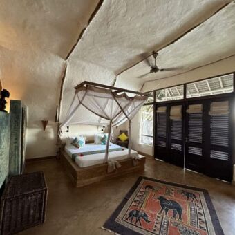 overzicht van een kamer met een groot bed, witte kalkmuren en plafond verder gedecoreerd met  strandmaterialen bij sunshine marine lodge