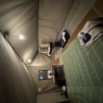 binnen in een safari tent van kati kati zie je een groot twee persoons bed met groene lakens