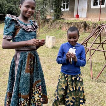 twee jonge Tanzaniaanse meisjes die voor hun huis staan bij mufindi highlands