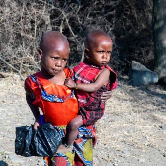 Bezoek aan een Masai Boma waar twee kinderen staan en die je aankijken. Reisverslag culturele activiteit rondreis Tanzania
