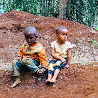 Reisverslag rondreis Tanzania. Twee kleine kinderen in smoezelige kleding zitten op de grond in de buurt van Rhotia Valley.