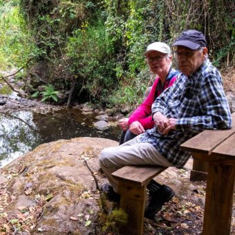 Man en vrouw die op een bankje zitten bij een rivier in de buurt van de Kilimanjaro Tanzania. Reisverslag rondreis
