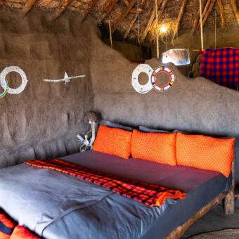 Mooi opgemaakt tweepersoonsbed met fel rood gekleurde deken in de Masai Lodge Tanzania. Review safari Tanzania