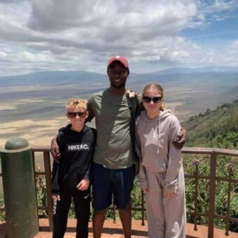 Bij het uitzichtpunt over de Ngororongo krater staat de gids met twee kinderen