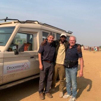 2 reizigers met hun gids bij de safariauto van droomreis tanzania op de Serengeti