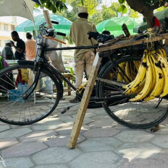 fiets met een stok als standaard en een tros bananen aan de pakjes drager