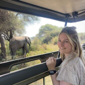 Reizigers van Droomreis Tanzania staand in de safariauto met op de achtergrond een olifant