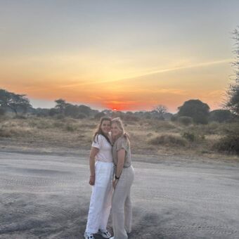 twee reizigers poseren met de ondergaande in Ndutu Tanzania