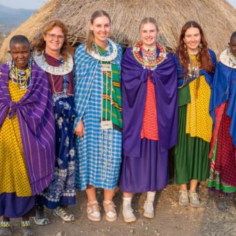 Reizigers in traditionele Masai kleding  poseren samen met de Masai
