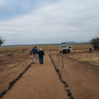 moeder van 90 die samen met iemand van de lodge naar de safari auto loopt