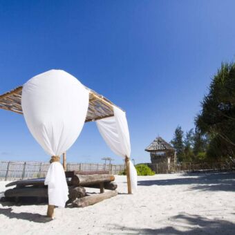 Strandbed met opbollende gordijnen in de wind