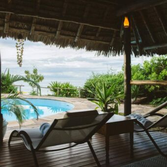 Vanuit de veranda van de lodge kijk je uit op het zwembad met daarachter de Indische Oceaan