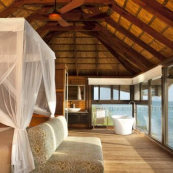 Wit bed met klamboe en uitzicht over de indische oceaan