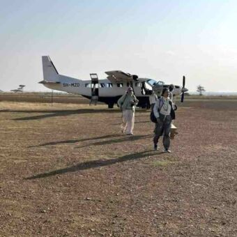Mensen die uit een klein vliegtuigje komen op een airstrip in de Serengeti