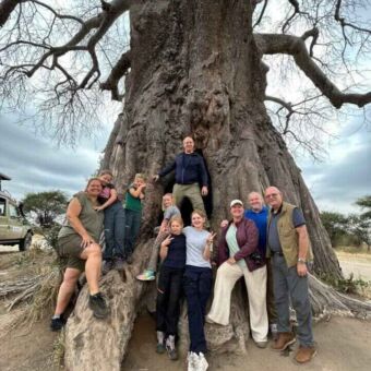 Grote familie aan de voet van een reusachtige baobab tijdens een safari in Tarangire Tanzania