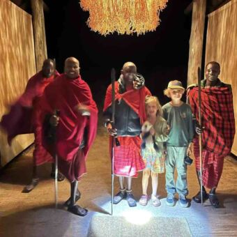 vier masai mannen met daartussen twee kinderen die lachen