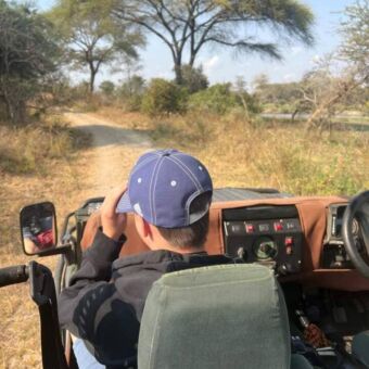 Jongen met petje in een open safari auto tijdens ee gamedrive in Katavi