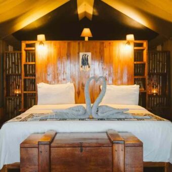 Mooi opgemaakt bed in een safari tent met de handdoeken als twee zwaantjes