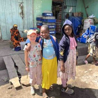 meisje met Tanzaniaans meisje lachend en arm om de schouder