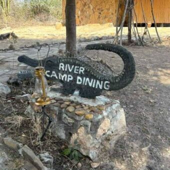 houtsnijwerk van een krokodil met daarop een tekst naar de dining van de lodge