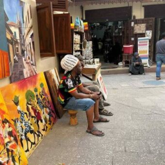 Zittende man die schilderijen verkoopt in Stone Town Zanzibar