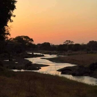 Zonsondergang waarbij de lucht oranje kleur en de Ruaha rivier ook