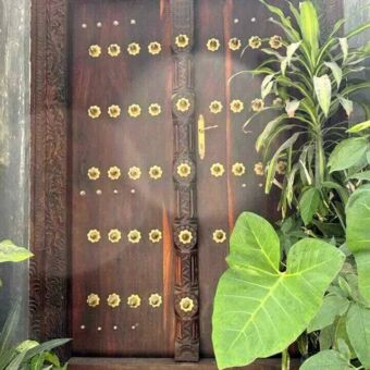 Donker bruine deur met koper beslag en veel houtsnijwerk