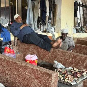 Een liggende slapende man bij zijn viskraam in Stone Town