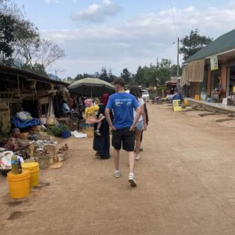 Jongen en vrouw lopen door een dorpje over een zandweg in Tanzania