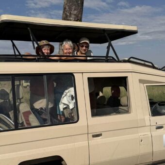 Twee vrouwen en een man staand nder het opgeheven dak van de safari auto van Droomreis Tanzania