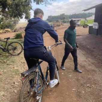 jongen op een fiets met daarachter een man die loopt bij Simba Farm