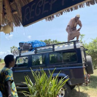 Landrover met een man er bovenop en hij laad allemaal spullen