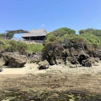 Vanaf de kust uitzicht op de accommodatie met overkapping bij de lodge in Pangani