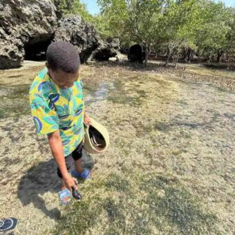 Man staand aan de kust in het lage water van de Indische oceaan en probeert te vissen met zijn handen
