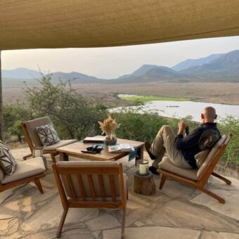 Man zittend op de vernanda van zijn lodge met een prachtig uitzicht over Mkomazi