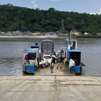 Oprit naar een veerboot met daarop veel mensen en een auto