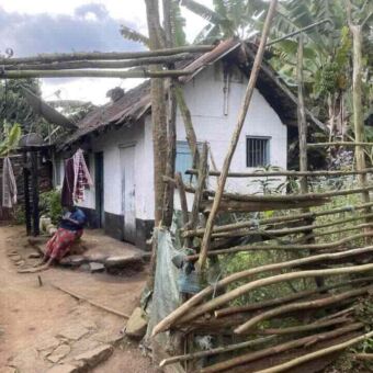 vrouw zittend op het stoepje van haar kleine bescheiden huisje