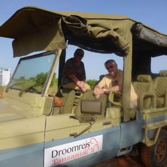 Reizigers van Droomreis Tanzania genieten van het uitzicht vanuit een open safari-auto.