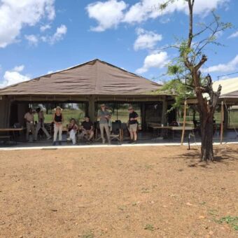 Reizigers staan en poseren op de veranda van de dining tent in Tanzaniaanse zon