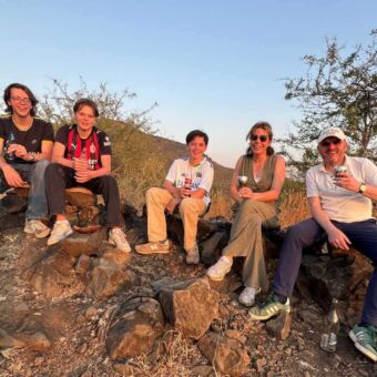 Familie geniet van een drankje tijdens zonsondergang op een rotsachtige heuvel in Tanzania