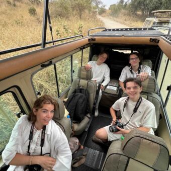 Familie met camera's zit klaar voor een gamedrive in een safariauto met open dak
