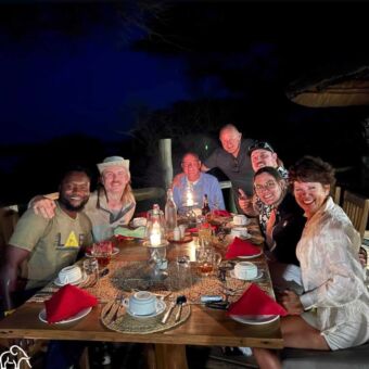 Reizigers met hun gids genieten van een sfeervol diner bij kaarslicht in een safaricamp in Tanzania